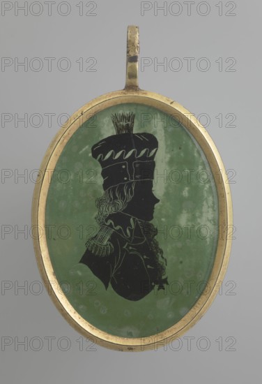 Tadeusz Kosciuszko in a general's uniform, profile silhouette. Black silhouette on a light green background showing Kosciuszko's right profile with mid-long hair emerging from under a high cap with a brim and a ponytail on the crown; half-bust in uniform with epaulettes and a high collar, a scarf or ribbon at the neck from which a cross-order hangs. Background with lighter spots and abrasions to the right and above the head. Oval brass frame. Miniature, circa 1800, height 4.4 cm, width 3.2 cm., An oval pendant with a gold-colored metal frame containing a silhouette portrait on a mottled green background; the silhouette is black and depicts a person in profile wearing a tall hat with decorative top details and a garment with a high collar and textured shoulder decoration; the frame shows slight wear and the overall colors visible are gold, green, black, and shades of gray in the background.