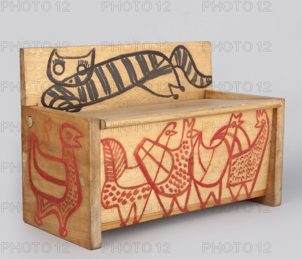Wooden bench from a set of doll furniture. Wooden bench with a box closed by a flap forming the seat; painted decoration with schematic animal silhouettes — a tabby cat on the backrest and chickens on the sides and front wall of the box. Toy, height 11.5 cm, width 17.0 cm, depth 8.0 cm. Made 1947–1948, Zakopane. Makers: State Secondary School of Fine Arts in Zakopane; Office of Production Aesthetics Supervision Warsaw co-creator; Antoni Kenar 1906–1959, sculptor., A small wooden box shaped like a bench with a backrest, decorated with hand-drawn animal figures. The backrest shows a reclining striped cat drawn in dark lines, and the front and side panels feature a group of bird-like figures drawn in a reddish color with patterned bodies and stylized legs and beaks. The wood has a light tan to beige tone, with visible grain and slightly darker edges. Colors visible include tan, beige, black, and red.