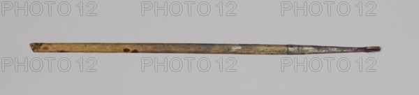 Jan Stanislawski's round brush; maker: Jan Stanislawski 1860–1907; role: painter; painting accessory: brush for plein-air painting; late 19th century; dimensions: height 13 cm, width 0.4 cm; varia., A long slender stick with a rounded end and a frayed tip lies horizontally against a light gray background, the stick showing a worn wooden texture in tan and brown with areas of darker brown and small dark spots, a few reddish marks along its length, and a section near the tip covered in dull metallic gray with traces of purple and darker brown at the very end.