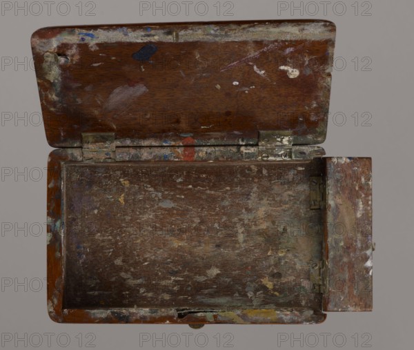 Jan Stanislawski's painting box; Jan Stanislawski 1860–1907 painter/creator; painting implements; artists in the open air; painting accessories; plein air studies; late 19th century; various; height 10 cm, width 16 cm, depth 3.5 cm, An open wooden box with a hinged lid showing worn, textured wood surfaces stained with paint splatters and smudges in colors including brown, white, blue, red, yellow, purple, green, and black; the interior bottom and sides are scuffed and mottled with similar paint marks and faded areas, and the metal hinges and hardware show tarnish and paint residue, while the background is a flat gray.