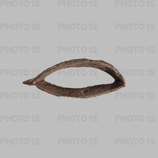 Eye setting, Small eye setting, possibly from a child's sarcophagus mask or a figurine's face, boat-shaped. Possibly from a sarcophagus mask or sculpture. Eyes, masks, faces; height 3 cm. Ca. 1550–332 BC New Kingdom–Late Period, Egypt. Unknown provenance., A roughly oval, hollow object with a textured, uneven surface in shades of brown and dark bronze sits against a flat light gray background; the object has a narrow pointed end on one side and a slightly wider curved opening on the other, with visible roughness and subtle shiny highlights on parts of its surface.