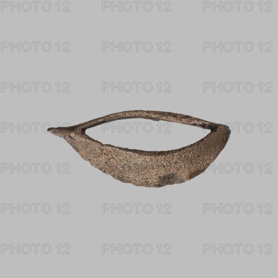 Eye setting, small eye setting, possibly from a child's sarcophagus mask or a figurine's face; boat-shaped; eyes; masks/faces; sarcophagus fragments ; ca. 1550–332 BC, New Kingdom–Late Period, Egypt; sarcophagus mask ; sculpture ; height 3 cm; unknown provenance., A textured, crescent-shaped object with a rough, granular surface in shades of brown and bronze sits against a flat light gray background; the object has an open center forming a hollow, with one end tapering to a small pointed tip and the opposite end broader and rounded, and the surface shows subtle variations of darker brown and metallic bronze highlights.