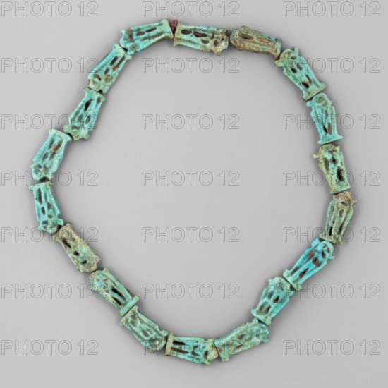 Necklace of 18 amulets, Goluchów Greater Poland Voivodeship, ankhs, Scen.Gal.Eg., necklaces, uas iconographic, ca. 1550–1295 BC; New Kingdom, 18th Dynasty, Egypt, amulet, jewelry, height 27 cm, A necklace composed of a continuous loop of similar carved beads arranged in an oval shape on a neutral gray background, the beads are elongated and slightly irregular with openwork sections and rough surfaces, showing a range of turquoise and green tones with areas of darker brownish and bluish discoloration and some subtle variations in patina across the pieces.