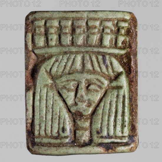 Amulet — plaque with the head of the goddess Hathor;, Hathor myth., Egyptian deities; plaque amulet with ankh iconography; ca. 1295–1069 BC, New Kingdom, 19th–20th Dynasty, Egypt; height 2.2 cm, width 1.8 cm, A rectangular carved object with rounded corners showing a stylized human face and headdress, rendered in a pale green color with areas of brown discoloration and darker spots; the carving includes vertical grooved lines suggesting hair, a central facial area with simplified eyes and nose, and a patterned band across the top, all set against a neutral gray background.