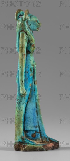 Amulet - figurine of a lion-headed goddess. A lion-headed goddess, in a tripartite wig and a narrow robe, walks with a lotus scepter in her left hand the right one is lowered. Presumably the goddess Sekhmet. Materials/type: amulet. Subject: lion-headed goddess, lionesses; Egyptian deities Sekhmet, Wadjit, Bastet suggested. Function: grave goods. Date: 664–332 BC, Late Period, Egypt. Dimensions: height 8.8 cm, width 1.7 cm. Maker: unknown., A slender standing figurine with a stylized animal head and elongated body rendered in a mix of bright turquoise, aqua, pale green, and spots of darker blue, with scattered patches of brown and rust-colored discoloration; the figure has an upright posture, long arms held close to the torso, a defined chest and hips, a long skirt-like lower garment, a rounded base with worn edges showing dark brown and reddish tones, and a small loop or hole near the back of the head.