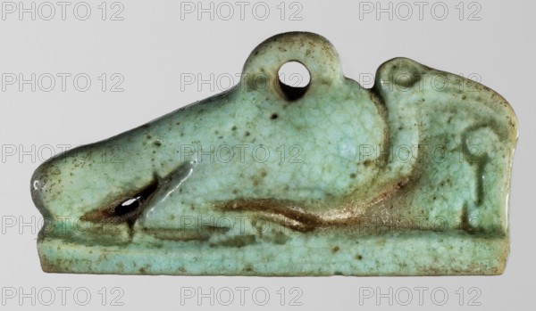 Amulet - ibis; creator, Goluchów Greater Poland Voivodeship; ibises, birds, pendants, sacred animals, Egyptian religion; 664–332 BC, Late Period, Egypt; amulet; height 1.7 cm, width 3.6 cm, A small glazed object shaped like a reclining animal with a rounded head and a loop near the top, shown against a plain light gray background; the object has a crackled surface glaze in shades of pale green and turquoise with areas of darker green and brownish discoloration and spotting, a glossy finish, a smooth rectangular base, a shallow raised ridge along the back, and a small dark cavity near the front that reflects light.