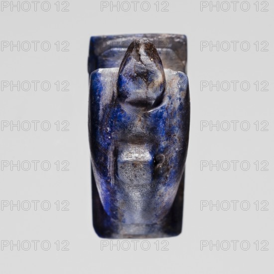 Amulet — vulture; creator, vultures, birds; pendant depicting a vulture sitting on a base with a loop/pendant on the back; New Kingdom, Egypt, ca. 1550–1069 BC; amulet; height 1.3 cm, width 1.8 cm., A small carved object with a smooth rounded top and a tapered body, shown against a light gray background; the surface exhibits a mix of deep blue, indigo, black, and patches of gray with subtle lighter blue highlights, and the carving shows worn smooth contours and small irregular pits and scratches.