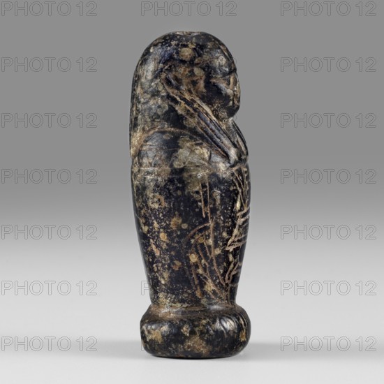 Amulet - god Osiris in hydria; maker, Osiris Kanopos mythology; Egyptian deities; Egyptian religion; 1st–2nd century AD, Roman period; Egypt place of discovery; amulet; height 4.9 cm, width 2.1 cm, A small carved figure depicted in profile standing upright on a rounded base, with a rounded head, stylized facial features, and arms crossed over the chest; the surface shows irregular mottling and worn areas in dark tones with patches of lighter brown and beige, and subtle variations of gray, set against a neutral gray background.
