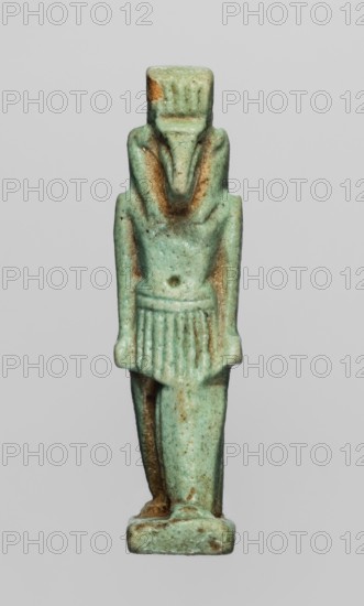 Amulet — god Thoth; object made of green faience; Egyptian; Late Period, 664–332 BC; amulet depicting Thoth Egyptian deity; height 5 cm, width 1.3 cm., A small standing figurine rendered in a greenish bluish hue with areas of brownish discoloration, showing a frontal humanlike figure wearing a short pleated garment and a distinct headdress, with arms down at the sides and hands near the hips, a stylized elongated face and beard shape, subtle textured surface pitting, and a rectangular base of the same greenish blue with brown spots.