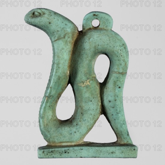 Amulet - Uraeus;, Uraeus, snakes, pendant; 664–525 BC; Late Period, 26th Dynasty, Egypt; amulet; height 3.8 cm, width 2.8 cm, A small carved object shaped like a stylized animal figure with a curved body and an open loop in its midsection, shown against a plain light gray background; the object is predominantly turquoise with areas of darker greenish-blue speckling and small patches of brown discoloration and wear, with a rounded head, a raised eye area, a small perforation near the top, and a flat rectangular base supporting the form.