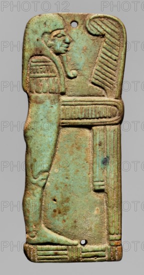 Amulet plaque in the shape of the god Imseti. Relief figurine shown in right profile as a mummy with a human head wearing a wig and divine beard. In front of the figure is an ostrich feather on a banner connected to the god's body by a piece of decorative material; a mat under the feet. Presumably an element of a mummy net. Sons of Horus mythology; Imseti mythology. Amulet; relief plaque. Date: 664–525 BC, Late Period, 26th Dynasty, Egypt. Height 6.1 cm, width 2.6 cm., A vertical rectangular object with rounded corners showing a raised carved figure in profile facing right, rendered in shades of green and turquoise with areas of brownish-beige patina and small dark spots; the figure wears a rounded headpiece and has a stylized eye, nose, and chin, with a short curved beard-like detail and a ribbed collar or garment across the chest; to the right of the figure a tall ribbed element rises and a horizontal ribbed band crosses the midsection, and a ribbed vertical element runs near the rig...