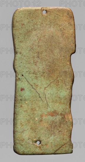 Amulet plaque depicting the god Hapi. Relief figurine shown in right profile as a mummified figure with the head of a baboon wearing a wig. In front of the god is an ostrich feather on a banner, connected to the body with a piece of decorative material. Mat under the feet. Presumably an element of a mummy net. Late Period, 26th Dynasty, Egypt, 664–525 BC. Amulet; height 6.2 cm, width 2.6 cm., A vertically oriented, irregular rectangular object with rounded corners and a few small holes near the top and bottom edges, showing a mottled surface in shades of green and brown with areas of lighter and darker green, rusty brown spots, thin darker vein-like lines and tiny pits, set against a uniform gray background.