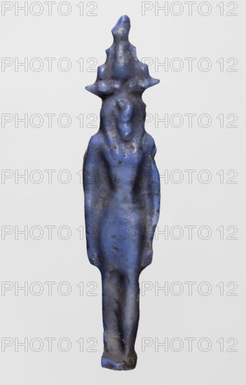 Amulet - Nehebkau, Nehebkau myth., Egyptian deities, Egyptian religion; dark blue glass; 332–30 BC, Ptolemaic Period, Egypt; amulet; height 4.7 cm, width 1 cm, A slender, vertically oriented blue figurine with a textured surface and signs of wear, showing a stylized humanlike form with an elongated torso and legs, a suggestion of shoulders and arms close to the body, and a raised headpiece that branches into several pointed protrusions; the object displays uneven blue tones with darker and lighter blue areas and small patches of brownish discoloration.