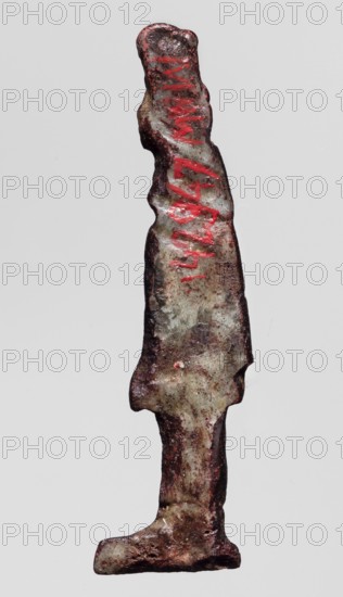 Amulet - goddess Hathor;, Hathor myth., Egyptian deity/goddess; red glass; Ptolemaic Period, 332–30 BC, Egypt; amulet; height 5.2 cm, width 1.3 cm, A vertical, narrow metal object resembling a stylized human figure with an elongated torso and base, showing an uneven, corroded surface with rough texture and irregular edges; the object displays a mix of colors including muted gray, brown, dark rust, and patches of reddish tones, with brighter red markings along the upper portion; the surface has areas of lighter greenish-gray patina and darker brown oxidation, with scattered shiny spots and small pits.