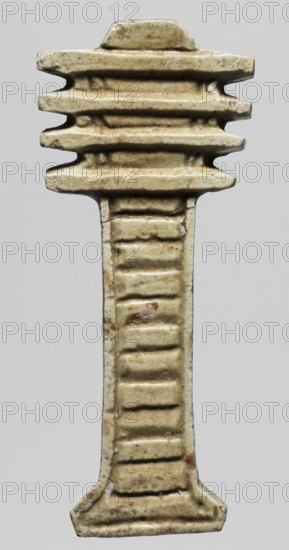 Amulet - djed pillar, Goluchów Greater Poland Voivodeship, djed pillar iconography, protective amulet for mummies, Egyptian religion, 664–332 BC Late Period, Egypt, amulet, height 6.5 cm, width 2.7 cm, An elongated, vertically oriented carved object with a symmetrical, flattened top and bottom and a narrower midsection, showing a stepped, ribbed surface along its length; the material appears glazed and worn with a smooth, slightly glossy finish, exhibiting colors of pale beige, off-white, light tan, and small patches of brown and rust tones, with subtle darker speckling and faint irregularities in the surface texture.