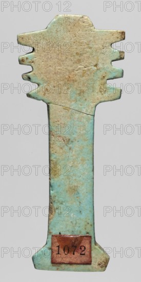 Amulet - djed pillar; creator, djed pillar amulet; protective amulet associated with mummies and Egyptian religion; Late Period, 664–332 BC, Egypt; material not specified; height 6.5 cm, width 2.7 cm., A vertical object with a long narrow shaft and a wider top and bottom, showing a weathered, uneven surface with patches and speckles; the predominant colors are pale turquoise and beige with areas of brownish discoloration, and a small rectangular piece of a darker reddish-brown material attached near the bottom; the top has a stepped, irregular outline on both sides and the bottom flares outward with rounded edges.