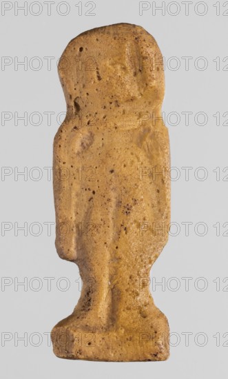 Amulet - tit, tit knots, protective amulets, grave goods, hieroglyphs, yellow glass; 332–30 BC, Ptolemaic Period, Egypt; amulet; height 3.3 cm, width 1.2 cm., A small carved figure-like object in shades of tan and light brown with darker brown speckles and small pits across its surface, showing a simplified upright human silhouette with a rounded head, subtle facial contours, narrow shoulders, and an elongated torso that tapers into short legs standing on a rectangular base; the surface appears textured and slightly uneven with areas of smooth wear and tiny darker inclusions.