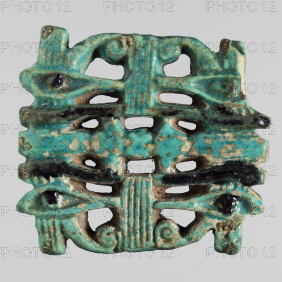 Amulet - quadruple udjat eye;, Openwork plaque with pairs of eyes separated by columns; udjat eyes; Egyptian religion; grave goods; mummies; ca. 747–656 BC, Third Intermediate Period, 25th Dynasty, Egypt; amulet; height 4.1 cm, width 4.8 cm, The image shows a small decorative object with a perforated, symmetrical form and a weathered surface; its dominant color is turquoise with areas of darker teal and black accents and patches where the underlying beige material is exposed, and there are traces of brownish discoloration; the piece features rounded protrusions, curved cutouts, and ridged vertical elements, with an overall rectangular outline and irregular edges.