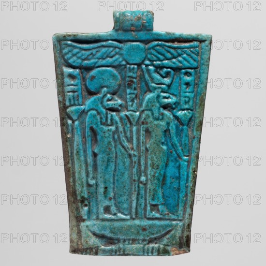 Amulet - Plaque with two lion-headed goddesses, Sekhmet myth., uraeus, solar disk, Uadj scepter, cartouches; Egyptian deities; Late Period, Egypt, 664–332 BC; amulet; height 7 cm, width 4.5 cm, A rectangular turquoise-blue faience plaque with a trapezoidal outline, showing a raised design of two standing anthropoid figures with bird heads facing right beneath a winged disk at the top; the surface shows variations of turquoise and teal with darker blue-green areas and small brown spots and weathered patches; the edges are slightly irregular and one corner shows a small chip exposing a duller brown material; the background is pale gray.