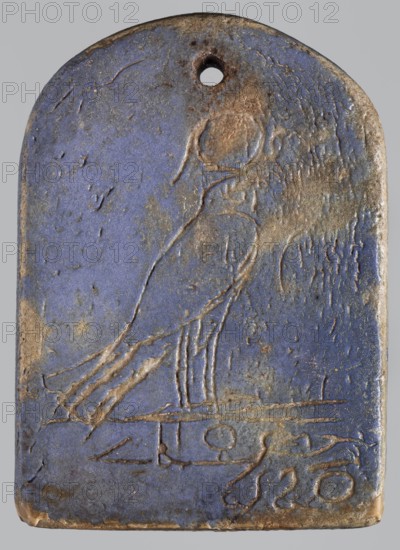 Amulet — stele with a depiction of the god Ptah and a falcon on the reverse; maker, Ptah mythology; falcon iconography; naos; plaques; Egyptian deities; Late Period, 664–332 BC, Egypt; amulet, stele; height 7 cm, width 5 cm, A rectangular pendant with a rounded top and a small circular hole near the top edge, made of a blue material with worn areas showing brown and tan erosion; the surface has incised lines forming the outline of a standing bird with a rounded head and a long tail, and a few horizontal incised lines near the lower area; the blue field shows patches of darker and lighter blue, and the edges and incisions reveal brown and beige tones.