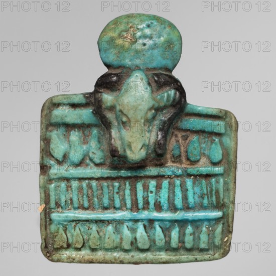 Amulet - ram's head, Goluchów Greater Poland Voivodeship; ancient Egyptian art; ram motif, necklaces, solar discs; rectangular necklace; ca. 1069–ca. 656 BC, Third Intermediate Period, Egypt; amulet; height 4.2 cm, width 3.4 cm., The image shows a small turquoise-blue glazed amulet with a rounded top and a rectangular lower section; a stylized animal head protrudes from the upper center with darker blue-green and blackish areas around the eyes and snout, and the rectangular area beneath features a series of raised horizontal and vertical ridges and teardrop-shaped motifs in varying shades of turquoise, aqua, green, and hints of brown where the glaze is worn.
