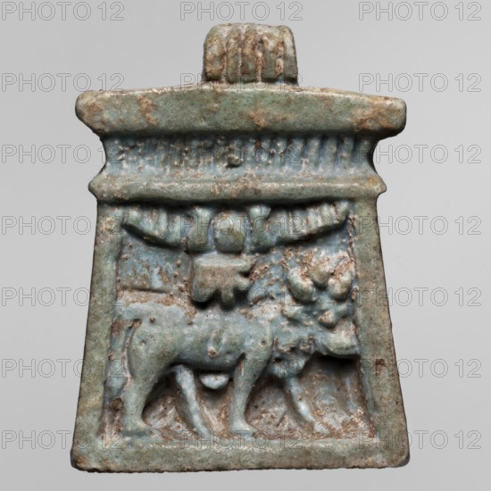 Amulet - naos, Goluchów Greater Poland Voivodeship, bulls, naos, udjat eyes, Apis myth., solar discs, sacred animals; depicting bulls, solar discs and udjat eye; ca. 1069–656 BC, Third Intermediate Period, Egypt; amulet; height 3.4 cm, width 2.5 cm, An aged rectangular pendant or amulet with a trapezoidal lower section and a wider top bar, rendered in weathered bluish-green and pale turquoise tones with patches of brown and tan surface wear, showing a raised relief of an animal with a stout body and short legs standing beneath a rounded central motif and a curved, wing-like element; the top area has a ridged loop or suspension feature and a band with vertical grooves, and the entire object displays rough, pitted texture and areas of discoloration in muted blue, green, brown, tan, and gray.