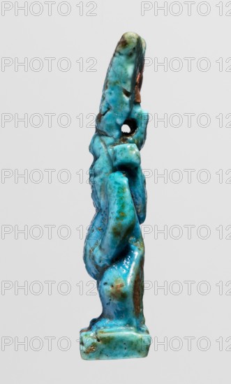Amulet - god Bes;, Figurine of Bes standing on slightly crooked legs, hands resting on his thighs, wearing a crown of four feathers. Blue faience with black feather tips. Egyptian deities; feathers. Late Period, Egypt, 664–332 BC. Amulet; height 4.8 cm, width 1.8 cm., A small vertical sculpture shown against a light gray background resembling a stylized standing figure with simplified limbs and an elongated head, rendered in bright turquoise and aqua tones with patches of darker teal and green, and areas of brownish and rusty discoloration; the surface appears glossy and slightly irregular with a visible round hole near the upper portion, and the base is a small rectangular platform in similar turquoise shades.