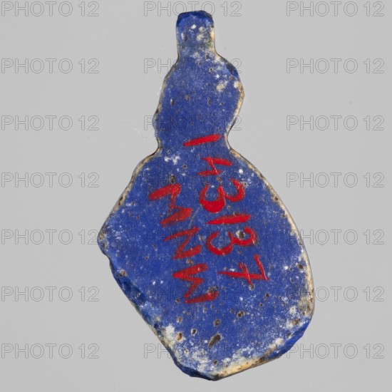 Amulet - god Horus-child;, Figure with tucked legs and a finger to the mouth; Horus myth., Egyptian deities, Egyptian religion. New Kingdom, 18th Dynasty, ca. 1550–1295 BC. Material: amulet. Height 2.9 cm, width 1.5 cm., A roughly bottle-shaped object with a vivid cobalt blue surface showing patches of lighter blue and small dark pitted spots, edged with areas of beige and off-white wear; there are several short red markings on its surface and a few tiny white flecks, all set against a plain pale gray background.