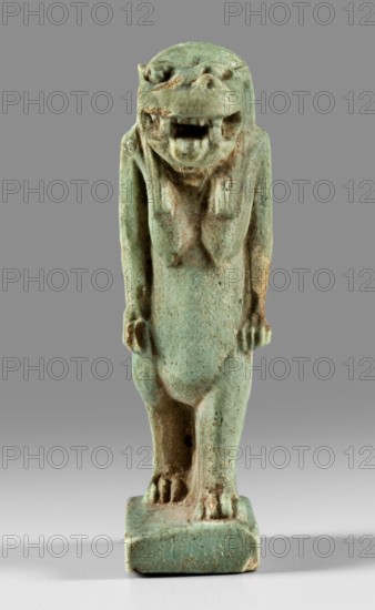 Amulet — figurine of the goddess Toeris in the form of a pregnant hippopotamus standing on lion legs and equipped with a crocodile tail; a stand under the legs and a pendant on the back. Toeris myth., Egyptian deities, crocodiles, hippopotamuses. 664–332 BC Late Period, Egypt. Amulet; height 5 cm, width 1.5 cm., A small carved figurine of a standing creature with a rounded head and an open mouth, rendered in a weathered greenish-blue material with areas of brown patina; the figure has elongated arms hanging at its sides, a slightly hunched posture, a stylized torso and legs ending in clawed feet set on a rectangular base, and the background is a smooth gradient of gray.