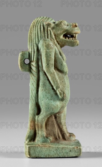 Amulet - goddess Toeris, Toeris myth., Egyptian deities, crocodiles, hippopotamuses. Figurine of the goddess Toeris in the form of a pregnant hippopotamus standing on lion legs and equipped with a crocodile tail. A stand under the legs, a pendant on the back. 664–332 BC; Late Period, Egypt. Amulet; height 5 cm, width 1.5 cm., A small sculpted figure of a standing lion-headed humanoid rendered in a green-blue glazed material with speckled darker spots, shown in profile facing right; the figure has a mane of vertical ridges, an open mouth with visible carved teeth, a rounded torso and arms held close to the body, and a short tail curving down the back. The surface shows areas of wear and exposed brownish material beneath the glaze. The figure stands on a rectangular base of the same green-blue color, and the background is a uniform medium gray.