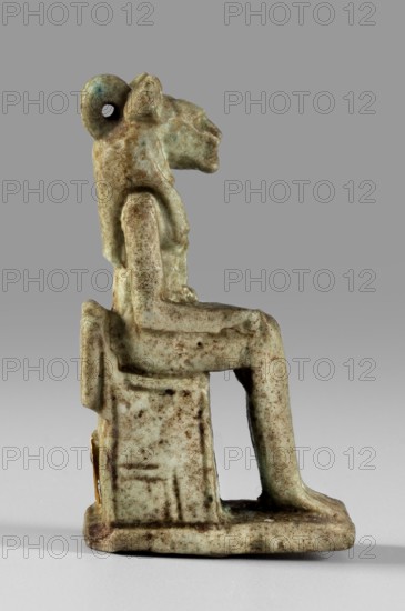 Amulet — figurine of a lion-headed goddess sitting on a throne Uajit? / Sekhmet?, limestone?, Late Period, Egypt, 664–332 BC; amulet; height 4.5 cm, width 1 cm., A small seated figurine rendered in muted green with areas of brown patina, shown in profile on a gray background; the figure has an animal-like head with a rounded loop at the back, a defined neck and shoulders, a torso and arms resting on the lap, and legs bent at the knees with feet on a flat base; the seat is rectangular and integrated with the base, and the surface shows speckled brown discoloration and wear across the green material.