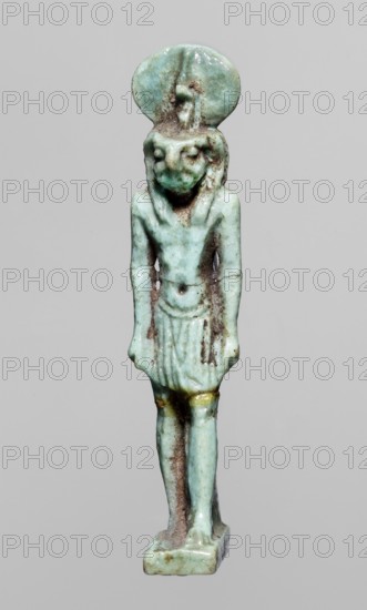 Amulet — god Re-Harakhte; maker, Re-Harakhte mythology; Egyptian deities; solar disk and uraeus iconography; Egyptian religion; Late Period, 664–332 BC, Egypt; material: amulet; dimensions: height 4.2 cm, width 0.8 cm, depth 1.3 cm., A small statuette of a standing figure in a bluish-green material with areas of brown discoloration, wearing a short skirt and a rounded headpiece, with an elongated torso and straight arms hanging at the sides, a rounded base supporting the feet, and small touches of yellowish color near the upper thighs.