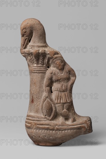 Lamp with a depiction of Athena-Neith, Lamp decorated with a youth, standing on its container, leaning against a column topped with a bird's head bent over a palm capital. The young man stands cross-legged, dressed in a garment that can be interpreted as a chiton or as Roman armor with pteryges, he has a Phrygian cap, on his head, and his right hand rests on a circular object a tambourine or rather a shield. Mithra mythology, Attys mythology, Phrygian caps iconography, figural lamps, Class.Gal.Scen., Athena mythology. 1st–3rd century, Egypt, oil lamp. Height 19.5 cm, width 9.7 cm, depth 4 cm., A sculpted object in shades of brown and tan sits against a neutral gray background; the piece has a rounded base and an upright form with a carved head resembling a bird at the top, a vertical column with decorative ridges and leaf-like motifs, and the carved relief of a human-shaped figure wearing a short skirt and holding a rounded shield-like object, all showing textured, weathered surfaces w...