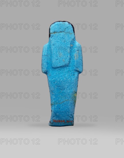 Queen Henuttawi's shabti, Henuttawi queen of Egypt; ca. 1100–1000 BC. Mummy-shaped funerary figurine made of blue faience with details in a dark color. Hands crossed on the chest, right over left; each hand holds a hoe. Three-part smooth wig finished with a border; uraeus above the forehead. Round face with clearly marked eyes and eyebrows. Wide bracelets on the wrists and a necklace with a silver ornament on the chest. Details of face, wig, tools and jewelry painted with black dye. Painted inscription arranged in three columns on the sides and in front of the legs reading: Ushabti of Osiris, the king's wife, Henut-tawi, with Osiris, the great god. ca. 1069–ca. 945 BC; Third Intermediate Period; 21st Dynasty; Deir el-Bahari, shabti; height 12 cm, width 4.6 cm., A small standing figurine shaped like a simplified human form with a rounded head and narrow body, rendered in bright turquoise-blue with speckled darker blue and lighter blue variations and visible hairline cracks and surface t...