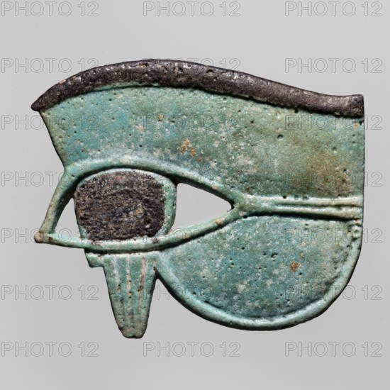 Amulet - udjat eye;, udjat eyes; mummies; grave goods; Egyptian religion; ca. 747–656 BC; Third Intermediate Period, 25th Dynasty, Egypt; amulet; height 6.5 cm, width 7.9 cm., A ceramic or metal object shaped like a stylized eye with a rounded lower lobe and an extended upper hood, rendered in shades of turquoise and green with areas of darker green and pale blue, a textured dark brown to black area forming the central pupil, a dark brown to black rim along the top edge, and small patches of light brown or tan scattered on the surface; the object shows a pitted, weathered texture and subtle raised lines defining the eyelid and lower teardrop element, all set against a plain light gray background.