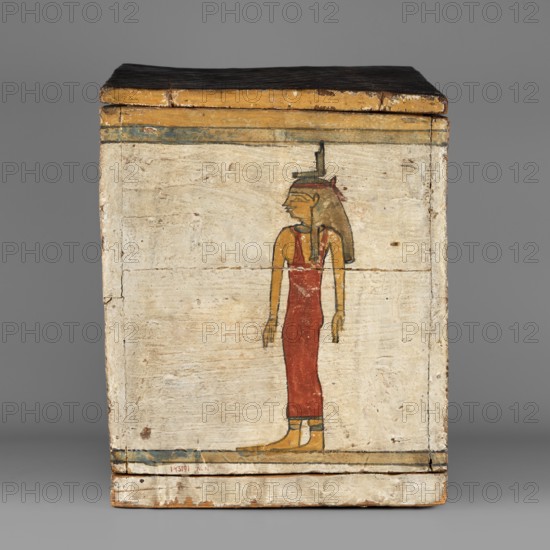 Canopic box, Sons of Horus mythology, falcons, jackals, Isis mythology, Nephthys mythology, grave goods, Egyptian deities, ca. 747–656 BC; Third Intermediate Period, 25th Dynasty, Egypt, canopic box, height 28.5 cm, width 22 cm, depth 29 cm, A rectangular wooden box with a hinged lid is shown, its surface painted and worn. The front panel features a painted figure in profile wearing a long red garment and a headdress, with skin tones in a yellowish-ochre and hair in a darker brown. The background of the panel is an off-white or cream color with visible wood grain and areas of distress, and there are narrow bands of faded blue and yellow near the top and along the bottom edge. The lid appears dark brown to black, and the lower edge of the box shows areas of exposed wood in a light tan color.