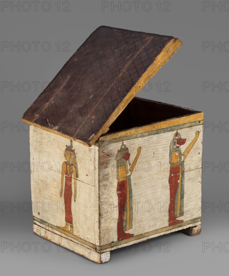 Canopic box, Sons of Horus mythology, falcons, jackals, Isis mythology, Nephthys mythology; grave goods; Egyptian deities; ca. 747–656 BC, Third Intermediate Period, 25th Dynasty, Egypt; canopic box; height 28.5 cm, width 22 cm, depth 29 cm; maker, Goluchów Greater Poland Voivodeship place associated., A wooden rectangular box with an open slanted lid showing a dark reddish-brown top surface with a faint diamond pattern and yellow-painted edges, the exterior sides painted a pale off-white with vertical figures in profile wearing long red garments and yellow and blue headpieces and accents, a few thin horizontal painted borders near the base in green and black, the interior appearing dark brown, and the whole object resting on small square feet against a gray background.