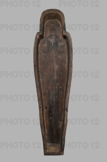 Sarcophagus of the gatekeeper of the temple of Amun Panepi, Panepy ca. 945–715 BC. Sacrificial formulas, necklace iconographic, wig iconographic, mummy straps iconographic, Nut mythological, hieroglyphs, grave goods, sculptured head. A small face with full cheeks painted red. Large eyes with black pupils and white irises. A green wig covering the ears frames the face. A loincloth above the forehead. On the chest is a large usekh necklace consisting of nine stripes. On the legs is a vertical strip of the Sacrificial Formula. On the bottom of the chest is an image of Nut marked with a black outline. c. 825–715 BC; Third Intermediate Period, late 22nd Dynasty, Western Thebes. Sarcophagus; height 187 cm, width 49 cm, depth 51 cm., A long, narrow, hollowed wooden object viewed from above with a tapered bottom and a rounded top, showing a carved interior surface with a faint linear carved figure near the upper area; the wood displays a range of brown tones from dark brown to lighter worn bro...