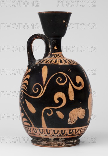 Red-figure aryballus lekythos with a scene of Aphrodite's toilet, On the belly: Aphrodite crouching and Eros handing her an alabastron; Eros mythology, Aphrodite mythology, Greek deities; beginning of the 4th century BC previously dated to the 2nd quarter of the 4th century BC; findspot Nola, origin Campania; vessel, lekythos aryballus lekythos; height 16.5 cm, width 19.5 cm, weight 0.23 kg., An oval-shaped ceramic vessel with a narrow neck and flared mouth, featuring a single curved handle connecting the shoulder to the neck; the surface is predominantly black with areas of natural clay orange exposed in decorative motifs, including flowing spiral and leaf-like patterns around the body and banded ornamentation near the mouth and base; the vessel shows small areas of surface wear where the black coating has flaked, revealing the orange beneath, and the base has an uneven, slightly worn rim with traces of residue; overall the colors visible are black and orange.