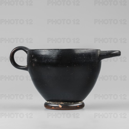 Black-finished skyphos, Type B. Thin-walled skyphos with a deep bowl and annular foot. One handle mounted horizontally, the other vertically. Entirely covered with a high-quality, glossy black varnish; only the bottom remains clay-colored with decoration of concentric circles. Technology: Visible traces of turning; small chips on the surface. Clay color 2.5 YR 5/6 red. Varnish color 10 YR 2/1 black. Attributed to Attica, 480–450 BC. Vessel skyphos. Height 7.6 cm; width 14.1 cm; depth 8.8 cm; weight 0.102 kg., A dark, glossy vessel with a rounded body and a narrow base, finished mostly in black with small areas where the underlying brown clay shows through; it has a single circular handle on one side and a short spout-like projection on the opposite side, with subtle surface wear and small scuffs visible on the black surface against a light gray background.