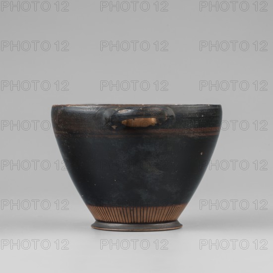 Black-finished skyphos. Thin-walled skyphos with a slightly inward-curved rim. Horizontal handles placed just below the rim, entirely covered with black varnish. On the outer surface, below the handle line, two red lines painted with thin brushstrokes. Entire body covered with black varnish. Lower part of the body, next to the foot, decorated with vertical lines rays? painted directly onto the clay; some rays extend onto the varnish. Low conical foot covered with varnish; varnish also on the inner surface of the foot. Bottom left the color of the clay, with a concentric-circle decoration and a central varnish stain. Inner surface entirely covered with varnish. Technology: visible turning lines; matte varnish. Colors: red 7.5 YR 3/2 dusky red; clay 2.5 YR 5/6 red; varnish 7.5 YR 2.5/1 black. Attributed to Attica; dated 480–470 BC. Maker: unknown. Vessel type: skyphos. Dimensions: height 7.3 cm; width 14.9 cm; depth 9.9 cm; weight 0.090 kg; foot diameter 5.4 cm; wall thickness 0.3 cm., A...