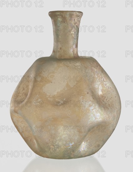 Flask, unknown eastern workshop, Goluchów Greater Poland Voivodeship, 3rd–4th century AD, vessel, height 11 cm, The image shows a rounded, irregularly shaped vessel with a short narrow neck and flared rim, appearing to be made of a glassy or ceramic material with a matte, weathered surface; its overall color palette includes beige and tan tones with iridescent sheens of pale green, pink, and pearly white, and there are areas of subtle mottling and surface texture that catch the light, creating a soft reflective quality against a plain light gray background.