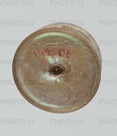 Cup, Egyptian workshop, Goluchów Greater Poland Voivodeship, 3rd–4th century AD, Roman Empire 27 BC–476, vessel, height 3.1 cm, width 3.2 cm, A round, slightly flattened object viewed from above with an iridescent surface showing green, pink, gold, and brown hues, a circular raised rim, a central small dark irregular cavity with surrounding darker brown discoloration, several small raised bumps and textured spots across the surface, and a plain light gray background.