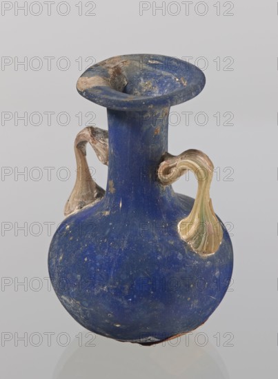 Amphora, bulging belly with a rounded bottom, long cylindrical neck with a thick ring-shaped rim; handles attached to the shoulders and halfway up the neck. 3rd–4th century, Roman Empire 27 BC–476. Vessel. Height 4.7 cm, width 3 cm., A blue rounded vase with a narrow neck and flared rim showing areas of surface wear, with a few decorative flowing handles in beige and pale green attached near the neck and shoulder; the vase surface also shows speckles and patches of lighter blue and small worn spots, set against a light gray background.
