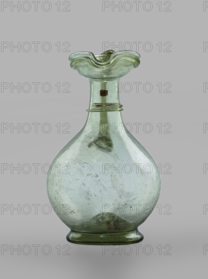 Oinochoe, Transparent, light green glass; spherical belly on a foot with a clearance, created by pressing inward the central part of the bottom of the vessel; decoration on the cylindrical neck in the form of a single glass thread of the same color, wound horizontally. The handle is glued to the arms and extends in an arc to the edge of the trefoil rim; free-blown. 4th century, Cyprus; vessel, oinochoe; base diameter 4.8 cm; weight 0.062 kg., A translucent glass vessel with a round body and a narrow neck topped by a flared, undulating rim, showing a pale green tint overall with subtle variations of lighter and darker green, a few areas with faint cloudy whitish streaks and some darker green spots, a group of small bubbles and imperfections visible within the glass, and a smooth green base.