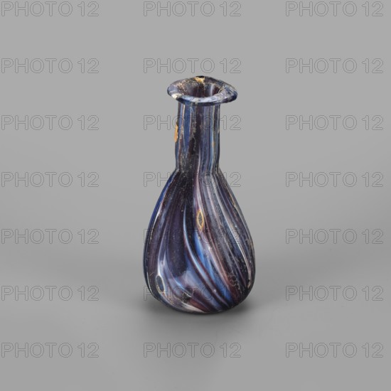 Unguentarium, unknown eastern workshop; glass vessel, Isings form 6/28. Translucent glass, mosaic: blue-violet-white. Pear-shaped body, cylindrical neck, rim tilted outwards and curved inwards, flattened; sagging/free blown. Late 1st century BC–first half of 1st century AD. Unguentarium; rim diameter 2.3 cm, base diameter 2.05 cm, weight 0.030 kg., A small bulbous glass vessel with a narrow neck and flared rim, standing on a smooth flat surface; the glass displays swirling bands and twisted striations in dark blue, deep purple, lighter blue, and hints of reddish tones, with a few oval spots of yellowish-gold and small areas of whitish wear or scratches visible on the surface.