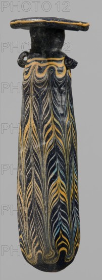 Alabastron, cylindrical belly, 4th–3rd century BC, vessel alabastron, height 17.4 cm, width 4.4 cm, A tall narrow vessel with a flared rim and small loop handles, primarily dark blue to black in color, decorated with flowing, featherlike vertical patterns in yellow and pale blue, with areas of lighter beige where the surface shows wear; the rim has a thin yellow edge, the neck is plain dark, and the patterned body tapers to a rounded base.