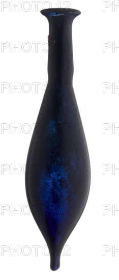 Vial, unknown eastern workshop, elongated belly with a pointed bottom, cylindrical neck and flared spout. Navy blue glass. 4th century, vessel, height 13 cm, width 1.8 cm, A tall, elongated vessel with a narrow neck flaring into a widened rim and tapering to a rounded point, shown upright against a plain background; the surface is dark with mottled areas of deep blue and lighter blue highlights, with subtle variations of black and dark gray tones; the texture appears slightly rough and uneven, with a small irregular patch of a lighter, brownish color on one side near the neck.