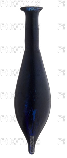 Vial, unknown eastern workshop, elongated belly with a pointed bottom, cylindrical neck and flared spout. Navy blue glass. 4th century, vessel, height 13 cm, width 1.8 cm, A tall, narrow vase-shaped object with a long neck and a flared rim, shown against a white background; the surface is predominantly dark blue to almost black with visible patches and streaks of brighter blue, a slightly rough texture, and areas of lighter wear near the top and bottom; the shape tapers to a pointed end and is smooth and symmetrical overall.