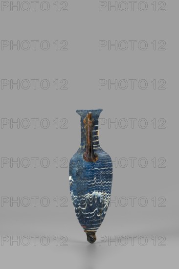 Amphorisko, Amphorisko with an ovoid belly, a long cylindrical neck ending in an uneven, slightly flaring rim, an uneven foot glued on, vertical, high, arched handles. Type: Grose III:E form III:2B, Harden form 7B. Opaque, dark blue glass decorated with white thread in a festoon pattern. The foot and vertical handles are made of dark amber, translucent glass; molding on the core. 2nd–1st century BC, Syria; vessel amphorisko; rim diameter 2.8 cm; weight 0.110 kg., A narrow, elongated vase with a rounded body tapering to a pointed base stands against a plain background, featuring a single handle running from the rim to the shoulder; the surface of the vessel shows a deep blue color with a pattern of wavy white lines and some areas of darker blue and lighter blue variation, and the handle and rim have brownish and slightly rust-colored tones.